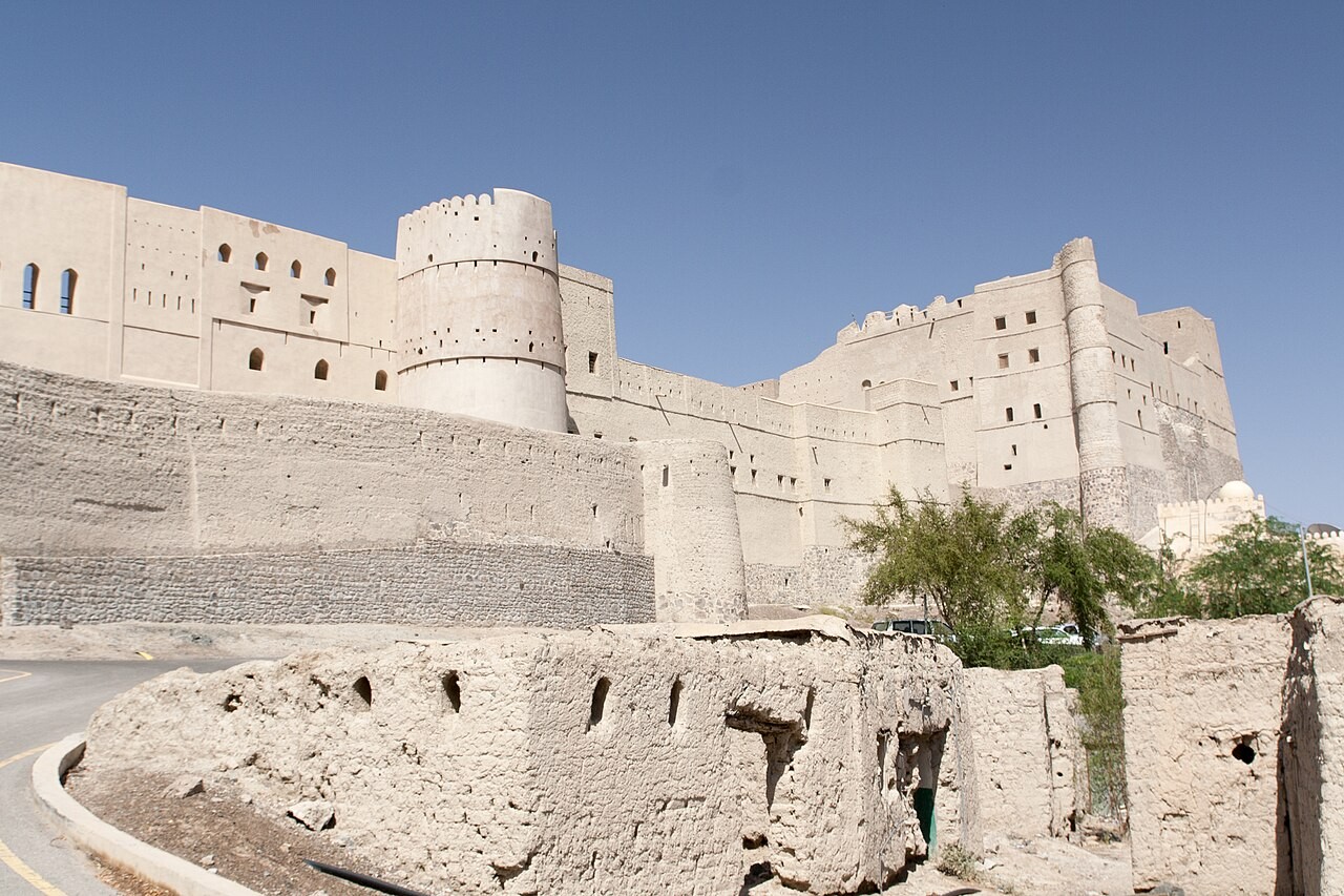 Festung Bahla mit hohen Lehmwänden und Rundtürmen über älteren Ruinen