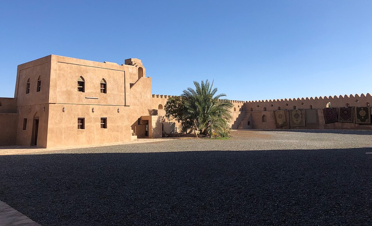 Innenhof von Schloss Jabrin mit sandfarbenen Mauern und Palme