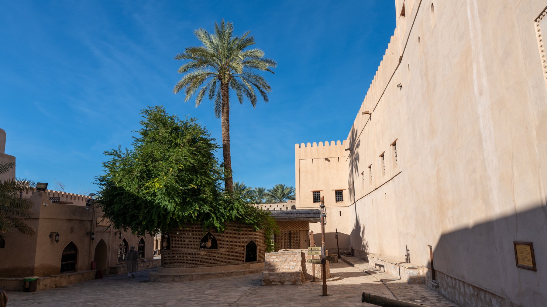 Innenhof der Festung von Nizwa mit Lehmwänden und Palmen