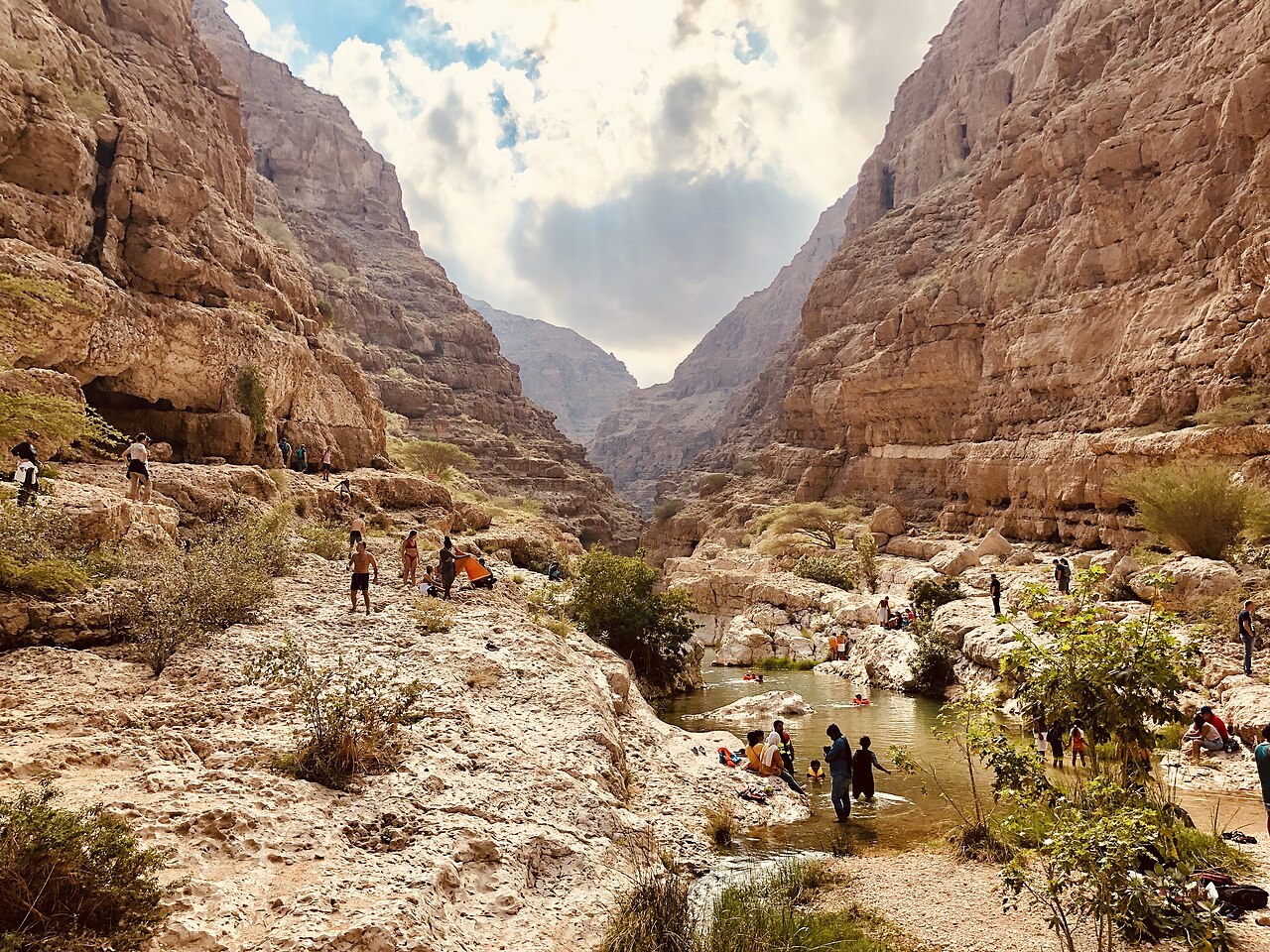 Wandernde auf dem felsigen Talgrund des Wadi Shab