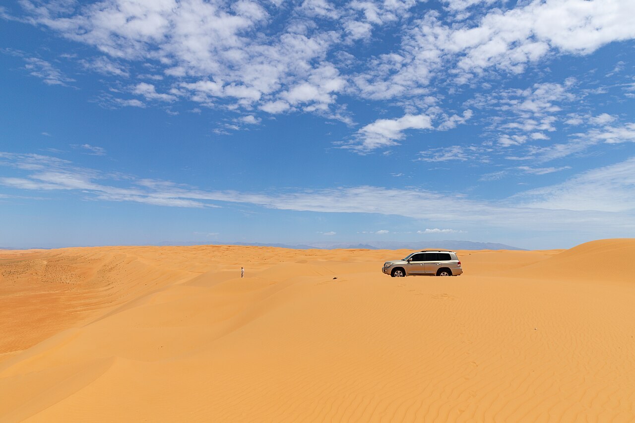 Geländewagen auf goldenen Dünen unter blauem Himmel in den Wahiba Sands